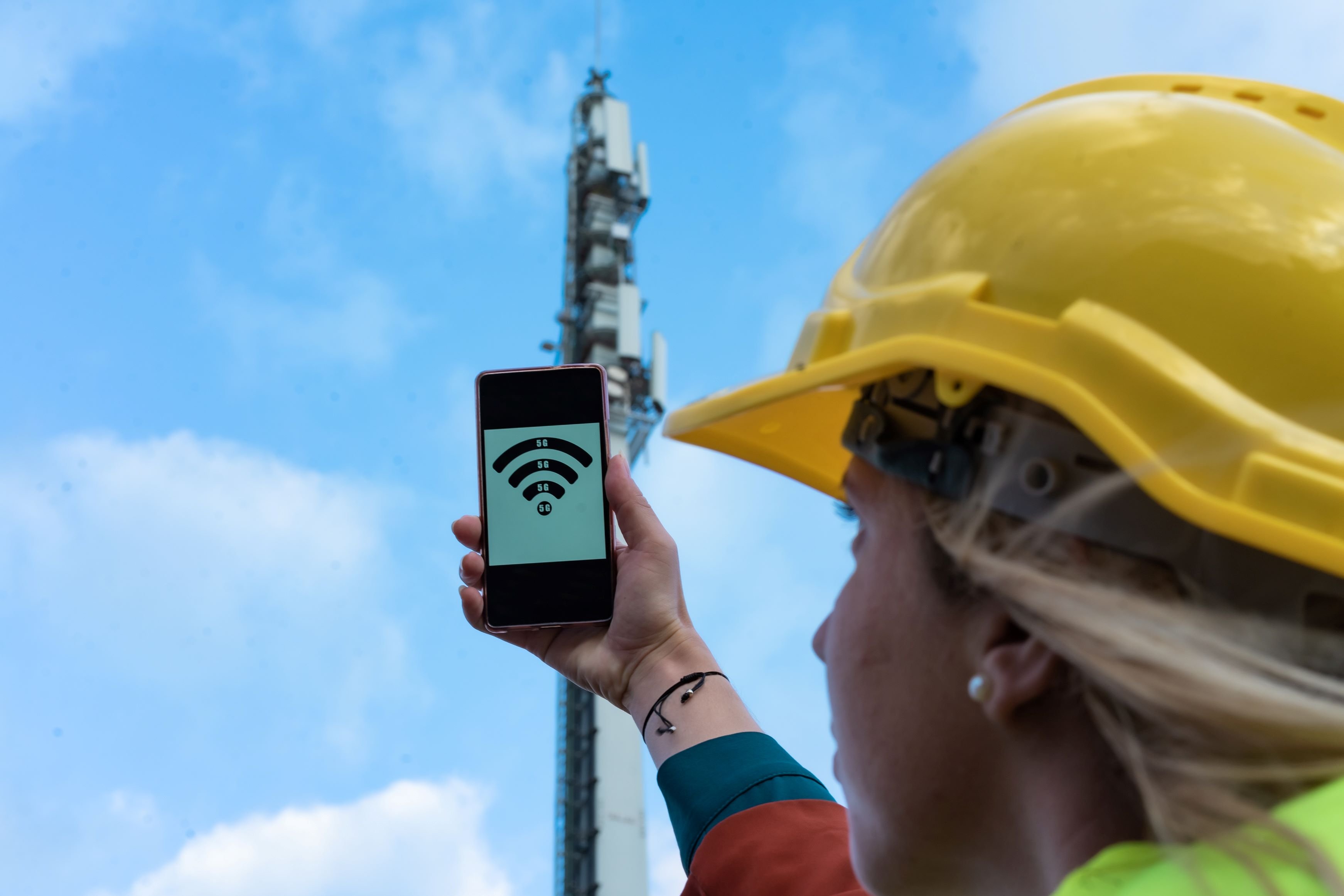 5G engineer holding phone to cell tower